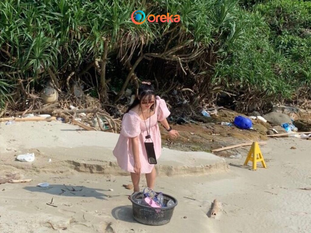 du lịch nhặt rác là gì. Hình ảnh khách du khách nữ đang thu gom rác, làm sạch bãi biển.