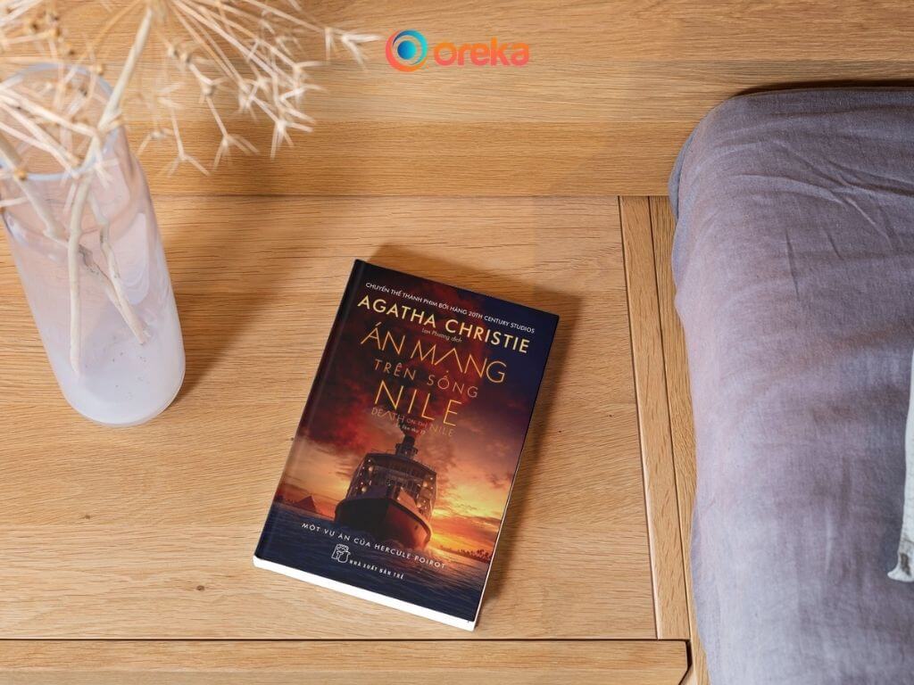 Án Mạng Trên Sông Nile: Review Tiểu Thuyết Trinh Thám Nên Đọc 3 Án mạng trên sông Nile review, hình ảnh cuốn sách được đặt trên tủ gỗ đầu giường, bên cạnh có một bình hoa khô