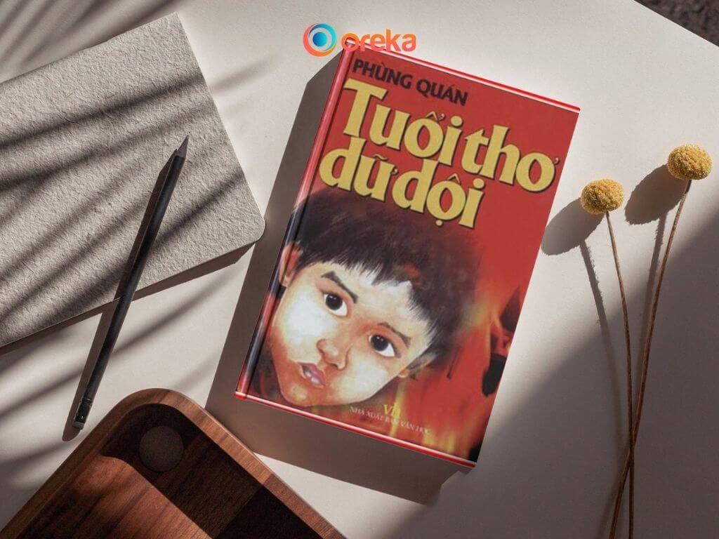 Tuổi Thơ Dữ Dội – Bản Anh Hùng Ca Về Những Chiến Binh Nhỏ Tuổi 2 review Tuổi thơ dữ dội, hình ảnh cuốn sách được đặt trên mặt bàn, bên cạnh có 1 cuốn sổ, 1 cái bút, 1/4 của khay gỗ và 2 cành hoa khô