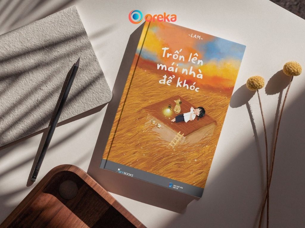 Review sách Trốn lên mái nhà để khóc. Hình ảnh cuốn sách được đặt trên bàn, bên cạnh có 1 cây bút chì, 2 cành hoa khô, 1/4 khay gỗ và 1/4 cuốn sổ